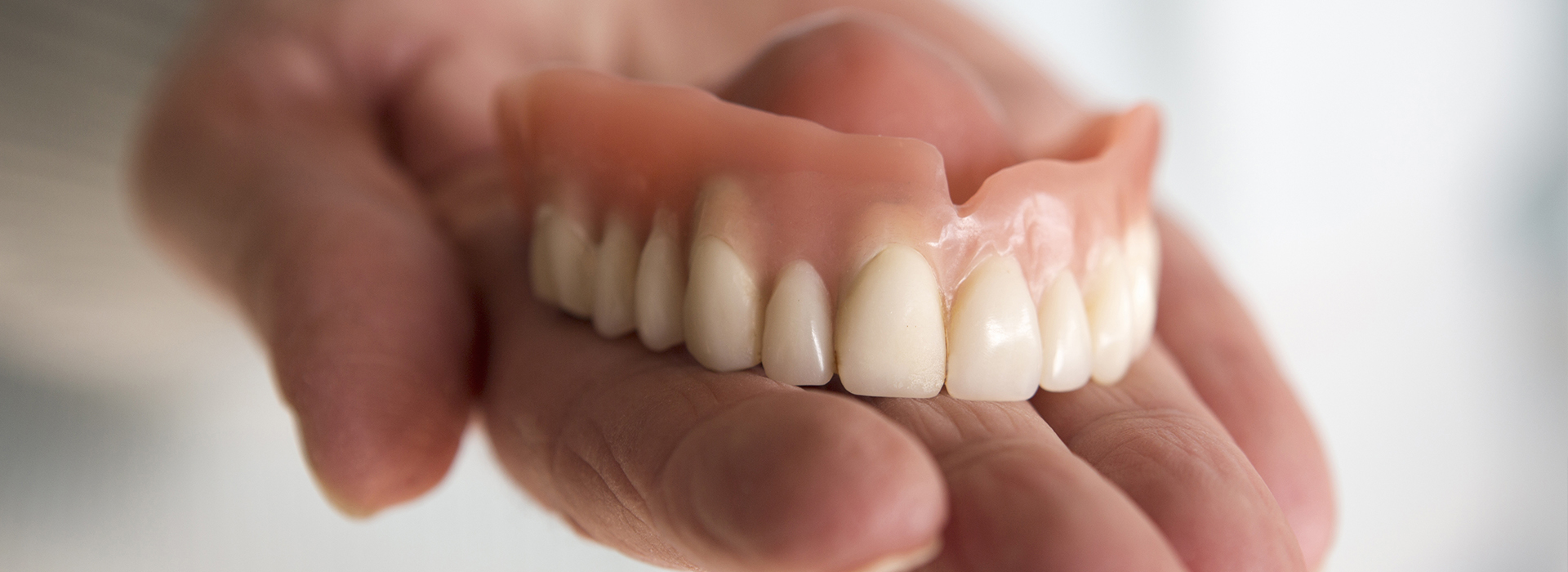 A person s hand holding a set of dentures.