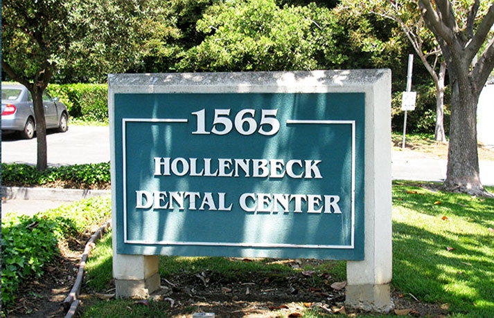 The image shows a street sign for  Hollenbeck Dental Center  at an address of 1650 Hollenbeck, with the year 2013 visible. The sign is mounted on a green post in front of a building with trees and a clear sky in the background.