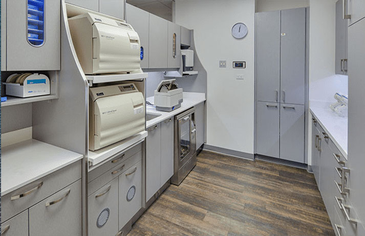 A medical office with a clean, white interior featuring a large desk area, cabinets, and equipment.