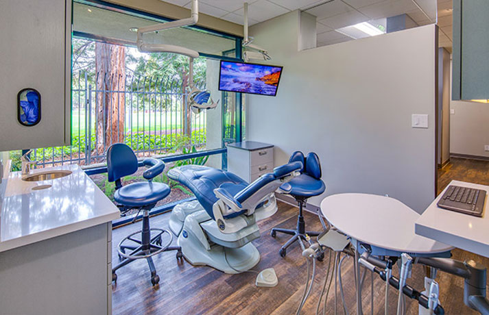 A modern dental office interior with a reception area, dental chairs, and equipment.