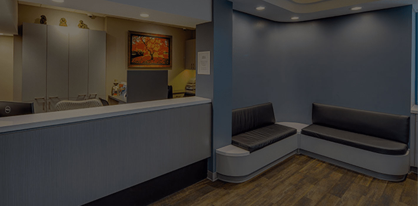 A modern waiting area with a minimalist design, featuring a reception desk, seating area with benches and chairs, and a large window.