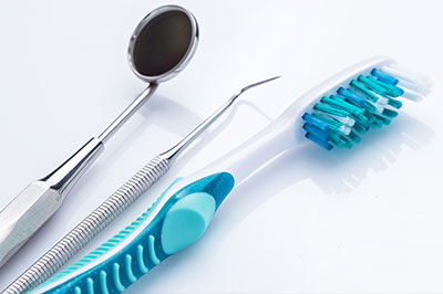 Toothbrushes and dental tools with a blue toothbrush holder in the foreground.