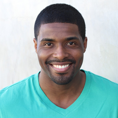 An elderly couple, a man with white hair and a beard, and a woman with short hair, both smiling warmly, posing closely together for a photograph.