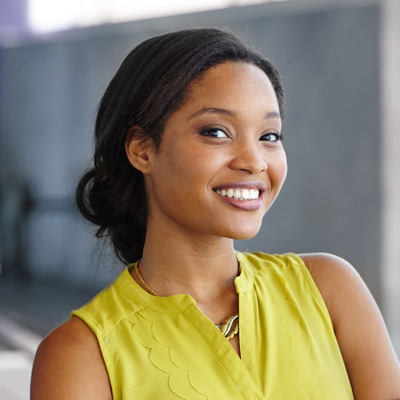 A woman with a radiant smile, wearing a yellow blouse, poses for the camera.