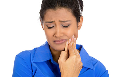 The image shows a woman with her eyes closed, holding her nose, and looking upwards with a concerned or pained expression.